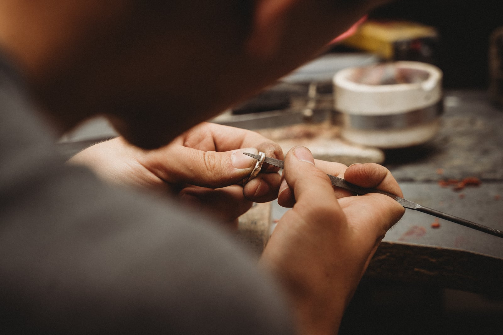 Gros plan sur des mains limant une bague en métal clair à l'établi